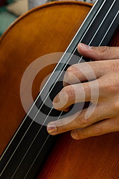 Detail of a hand placed on the neck of a cello to play a musical note