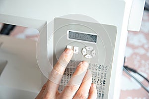 Detail of a hand pressing the button to select a stitch for machine sewing. Chart of sewing options for the electric machine.