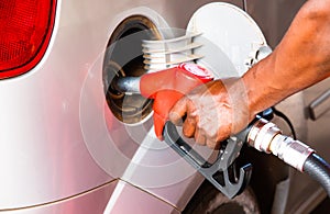Detail hand of worker man refuelling car at the petrol station. Concept photo for use of fossil fuels gasoline, diesel engine