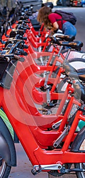 Detail of the handlebars and pedals of shared rental red bicycles parked in a row on a street in the city of Barcelona