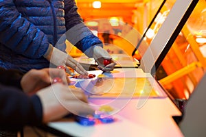 Detail on hands holding joysticks and red joysticks and playing a game on and old arcade