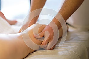 Detail of hands massaging human calf muscle.Therapist applying pressure on female leg. Hands of massage therapist
