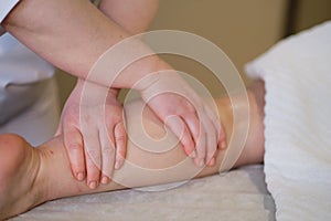 Detail of hands massaging human calf muscle.Therapist applying pressure on female leg. Hands of massage therapist