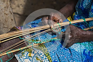 Detail of the hands of an old woman working in front of her hut at the village of Eticoga in the island of Orango