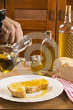 Detail of a hands pouring olive oil on a slice of bread