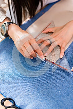 Detail of hands with scissors at tailor shop cutting cloth