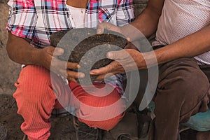 Detail of the hands of a stone laborer to make molcajetes, giving it to the female hands of an elderly Mexican woman.