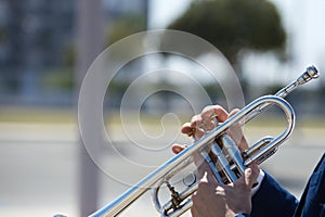 Detail of the hands of a trumpet player playing the musical instrument. The hand raises and lowers the pistons of the trumpet.