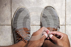 Detail of the hands of a young Brazilian man tying the tennis shoe
