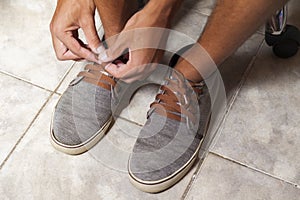 Detail of the hands of a young Brazilian man tying the tennis shoe
