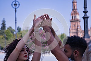 Detail of hands of young multi-ethnic couple making figures while dancing bachata sensually outdoors