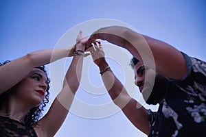 Detail of hands of young multi-ethnic couple making figures while dancing bachata sensually outdoors