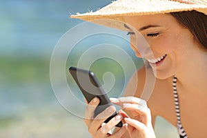 Detail of happy tourist using phone on the beach