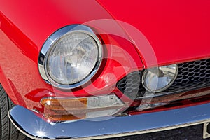 Detail of an headlight of a vintage italian red sport car