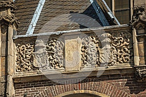 Detail of high relief stone sculpture of coat of arms in old church facade of Amsterdam.