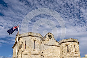 Detail of the historic prison in Fremantle, Western Australia, with the Australian flag blowing in the wind against a dramatic sky