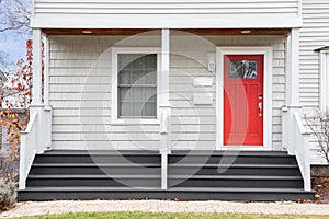 Detail of a home\'s front porch and red front door.