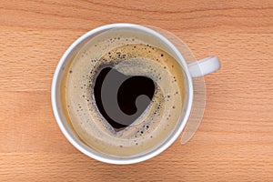 Detail of hot black coffee with foam making the heart-shape on t