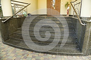 Detail of a house facade. New granite stairs with metal railings