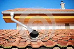 Detail of house roof with water spout and small chimney