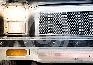 Detail of Illuminated Headlight and Grille of Car