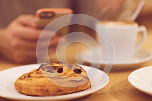 Detail image of unrecognisable man drinking coffee and holding smart phone while having breakfast in restaurant.