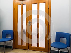 Detail of the interior, design - wide wooden doors and two office chairs next to them