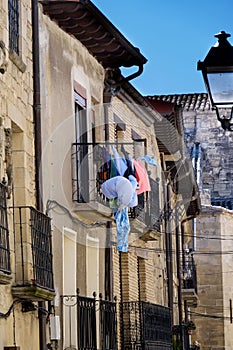 Detail of an iron balcony with clothes hanging to dry in a stone