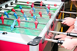 Detail of kid`s hands playing the foosball table match. Soccer game, friends recreation