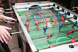 Detail of kid`s hands playing the foosball table match. Soccer game, friends recreation