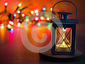 Detail of a lantern with tea candle and Christmas lights in background