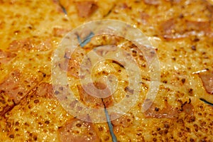 Detail of a large family pizza with ham, bacon and cheese cut in slices for a fast food shared with friends and family