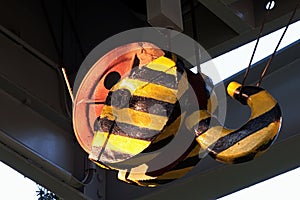 Detail of large industrial double pulley hook painted with yellow and black stripes, placed on gantry bridge portal crane.