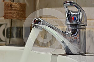 Stream of water falling from a faucet in a sink photo