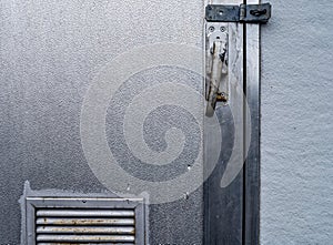 Detail of the latch and vent on a shiny metal utility building