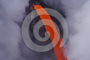 Detail of Lava flowing out of cliff suround with white cloud steam