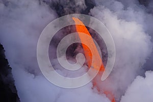 Detail of Lava flowing out of cliff suround with white cloud steam