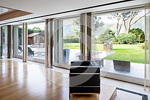 Detail of leather armchair and window with garden and pool view