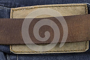 Detail of leather belt on a blue jeans