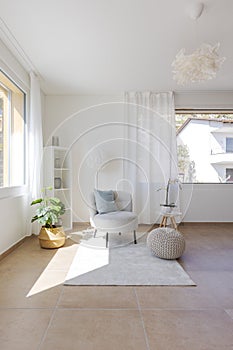 Detail of a living room corner with a small armchair with a coffee table and a pouf resting on the carpet