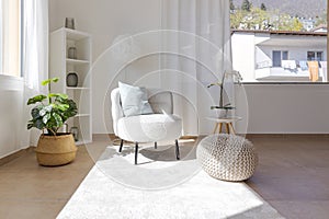 Detail of a living room corner with a small armchair with a coffee table and a pouf resting on the carpet