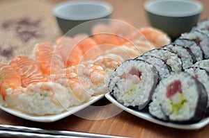 Detail of maki sushi rolls and nigiri sushi with salmon and shrimp japan food on the table with soy sauce and ginger