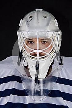 Detail of a male face in a white goalie hockey mask and  colorful lights.