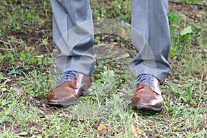 Detail man in gray suit with brown shoes and blue laces