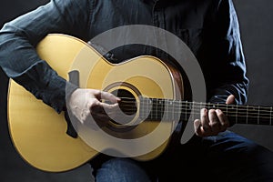 Detail of man playing acoustic guitar.