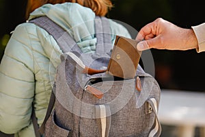 Detail of a man`s hand stealing a wallet from a woman`s backpack