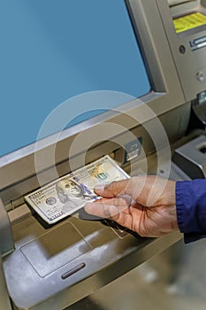 Detail of a man's hand taking dollar bills out of an ATM