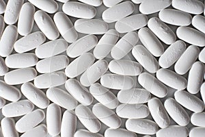 Detail of many white pills of medicines produced by the pharmaceutical and health chemistry industry, seen from above