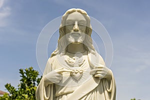 Detail of marble statue of Jesus Christ with heart in a temple and blue sky background in Danang, Vietnam