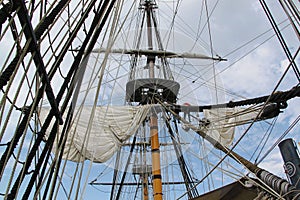 Detail of mast of ship. Detailed rigging with sails. Vintage sailing ship block and tackle.